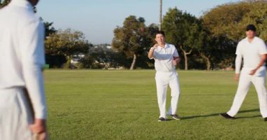 Erkek kriket oyuncusunun attığı kırmızı topu çimlerin üzerinde, kopyalama alanında yakalıyor. Spor, takım çalışması, atletizm, eğlence, açık hava, eğlence, rekabet