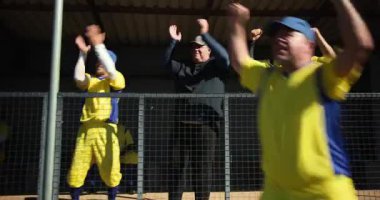 Son sınıf beyzbol oyuncuları ve koç bekledikten sonra çitlere yumruk sallıyor, galibiyeti kutluyorlar. Sporcular, takım çalışması, zafer, yoldaşlık, eğlence, sportmenlik, açık hava