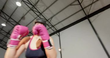Kamera vardiyası, pembe eldivenli bayan boksör eşine ringde antrenman yapması için yumruk atıyor. Savaş, atletizm, güç, kararlılık, yoğunluk, eylem, uygunluk