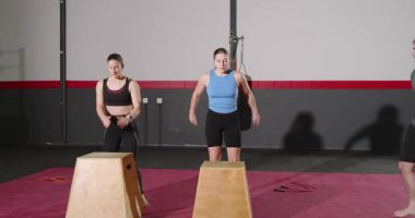 Spor salonunda form ve zamanlamayı düzeltirken iki stajyerin kutulara atlamasını işaret eden beden eğitimi hocası. Güç, egzersiz, antrenman, atletizm, kararlılık, motivasyon, eğitim