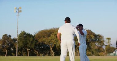 Çeşitli kriket takımları sahada kırmızı top, vurucu sopa sallıyor ve saha oyuncusu topu yakalıyor. Atletik, takım çalışması, rekabet, sportmenlik, aksiyon, açık hava, canlı