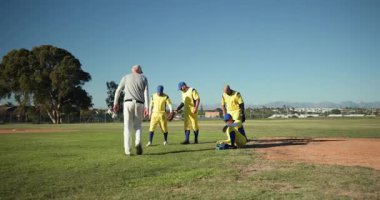Sol üst düzey koçtan atıcının atış sahasının yakınındaki oyunculara el uzatarak birliğe teşvik etmek. Akıl hocalığı, takım çalışması, liderlik, atletizm, topluluk, açık hava, motivasyon