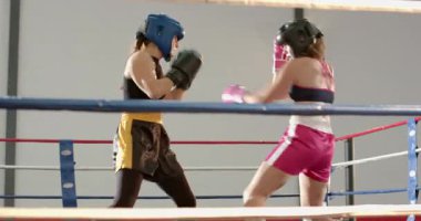 Boks ringine giriyoruz, kadın boksörler daireler çiziyor, yumruk atıyor, maç kazanmak için yumruk atma pozisyonu alıyor. Dövüş, spor, atletizm, güç, eğitim, kararlılık, spor