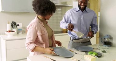 Yumurtalarını bitiren çeşitli çiftler çırpılmış yumurta ve tereyağlı tostu mutfakta yiyorlar. Kahvaltı, çift, modern, mutfak, aşçılık, sabah, samimiyet.