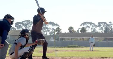 Erkek vurucu sahadaki atıcıdan hızlı topa vuruyor ve topu kaçırıyor, hakem elini kaldırıyor. Atletizm, spor, yarışma, açık hava, atletizm, aksiyon, eğlence