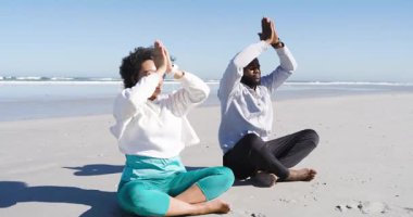 Kapüşonlu kapüşonlu, spor saatli, yoga akışı antrenmanı yapan çeşitli arkadaşlar kıyıya geliyor. Sağlık, huzur, uyum, farkındalık, açık hava, spor, rahatlama.