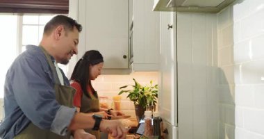 Asyalı çift modern mutfakta yemek pişiriyor, tencere ve tavayla yemek hazırlıyorlar. Aşçılık, ortaklık, aşçılık, mutfak, takım çalışması, hazırlık, ev