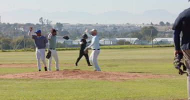 Yakalayıcı, tümsekte erkek takım arkadaşlarının kıvılcımlarını saçıyor eldivenlerini tokatlıyor, kutlama yapıyor ve yürüyüp gidiyor. Atletizm, takım çalışması, kutlama, zafer, dostluk, sportmenlik, açık hava