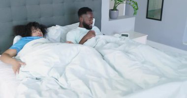 Yatak odasında yorgan çeken Afro-Amerikalı bir adam uyandı ve yatak hazırlıyor. Romantik, rahat, uyum, ev, iç mekan, yaşam tarzı, konfor