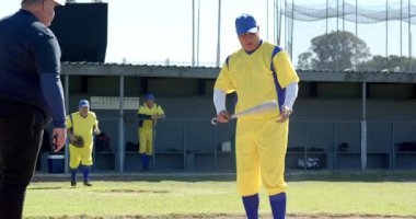 Yetişkin erkek vurucu döner ve sopa vurur ve kale levhasında hakemlere atış hazırlar. Atletizm, sportmenlik, takım çalışması, rekabet, açık hava, aktif, eğitim