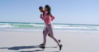 Güneş motive edici çeşitli arkadaşlar kumlu sahilde koşu ayakkabıları ile koşuyorlar ve ısınma hareketleri yapıyorlar. Açık hava, fitness, egzersiz, sağIık, yoldaşlık, aktif giyim, doğal