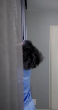 Dikey video: Mutlu çift pencerede kucaklaşıyor, evde birlikte sabahın tadını çıkarıyorlar. İlişki, romantizm, yaşam tarzı, evcil, samimiyet, rahatlama