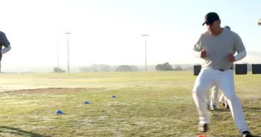 Koç Demo 'nun ardından çeşitli erkek beyzbol oyuncuları sahada kozalakları karıştırarak ayak hareketlerini geliştiriyor. Çeviklik, eğitim, takım çalışması, spor, açık hava, fitness, hareket