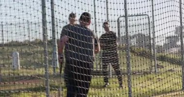 Koç beyzbol toplarını vurucu olarak fırlatıyor vuruş kafesinin içinde sallanıyor antrenman için ağlar, kopyalama alanı. Spor, antrenman, açık hava, hareket, atletik, takım çalışması, fitness