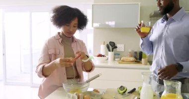 Afrika kökenli Amerikalı çift ev mutfağında yumurta çırpıyor, süt çırpıyor ve tavaya karıştırıyor. Aile içi, işbirliği, aşçılık, modern, yaşam tarzı, neşeli, rahat