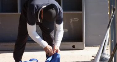 Olgun erkekler spor çantasına yaklaştıktan sonra yedek kulübesinde yarasa ve topları boşaltıp antrenmana hazırlanıyorlar. Atletik, takım çalışması, spor kıyafeti, aktif giysi, açık hava, motivasyon, eğitim