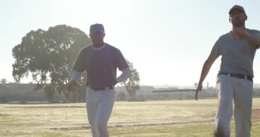 Sahadaki erkek oyuncuların üzerine atlamak, koşmak, yürümek, hamle yapmak ve beysbol toplarıyla antrenman yapmak. Atletizm, takım çalışması, fitness, açık hava, antrenman, hareket, spor