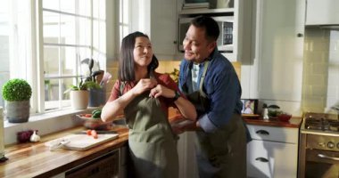 Olgun Asyalı bir çift modern mutfakta yemek pişiriyor, mutfak aletleriyle kesme tahtası ve demlik kullanıyorlar. Aşçılık, aşçılık, mutfak, ortaklık, modern, yemek hazırlama, nişan