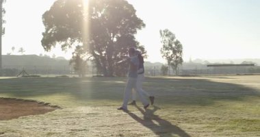 Çeşitli erkek takım arkadaşları İHA 'yı izliyor ve beyzbol teçhizatlarıyla gökyüzüne doğru el sallıyorlar. Sporcular, takım çalışması, sportmenlik, açık hava, şafak, zafer, yarışma