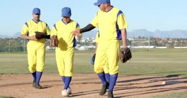 Vuruş yapan erkek beyzbol takımının saha içinde yürümesinden sonra en kısa boylu adam şapkasını çıkarıp eldivenle ter siliyor. Atletik, takım çalışması, günlük, açık hava, spor giyim, eğlence, rekabetçi.