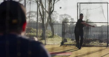 Yakalayıcı atıcıya işaret veriyor, topu döndürüyor ve rafine etmek için beysbol kafesine atıyor. Spor, antrenman, atletizm, takım çalışması, disiplin, pratik, açık hava