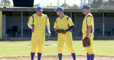 Erkek beyzbol takımının takım arkadaşlarının eldivenlerini ayarlaması ve sahada uçan topu izlemesi. Sporcular, takım çalışması, açık hava, spor, eğlence, aktif, rekabet