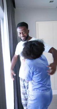 Dikey video: Pijamalı mutlu çift evde sabah güneşinin tadını çıkarıyor. Aşk, konforlu, mutluluk, rahatlama, yaşam tarzı