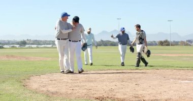 Kıdemli teselli atıcısı yürüyüp gittikten sonra çeşitli erkek takım arkadaşları sahada eldivenlerle tezahürat yapıyor. Sporcular, yoldaşlık, kutlama, sportmenlik, takım çalışması, açık hava, canlı