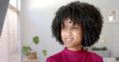 Afro-Amerikalı kadın kendinden emin gülümseme gösteren kameraya bakmadan önce tahta perdelere bakıyor. Portre, sofistike, rahat, doğal ışık, refah, yaşam tarzı, iç mekan