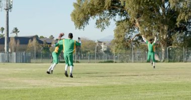 Yüksek uçan top farklı erkek takım arkadaşlarının takla atmasına ve dış sahada kutlama yapmasına neden oluyor. Sporcular, takım çalışması, eğlence, canlı, açık hava, rekabet, dostluk