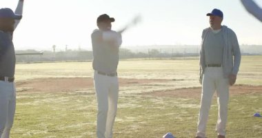 Kıdemli erkek antrenör iki oyuncuyu beysbol sahasında ısınma turu için çağırıyor, mavi konisiyle. Atletik, takım çalışması, egzersiz, antrenman, spor, açık hava, enerjik