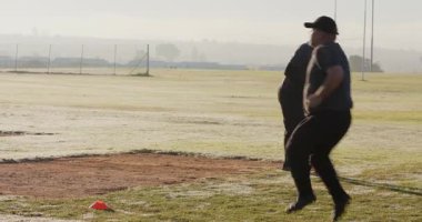 Kırmızı koni kare şeklindeki çeşitli erkek sporculara dönüşümlü olarak çimenleri ısıtmak için alıştırma yapıyorlar. Eğitim, spor, egzersiz, performans, hareket, spor, motivasyon