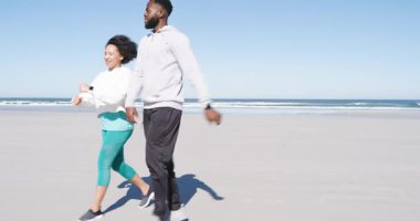 Çeşitli yetişkin koşucular nöbet tutuyorlar, plajda koşuyorlar, esniyorlar ve sonra da uzaklaşıyorlar. Fitness, atletizm, açık hava, arkadaşlık, sağlık, yaşam tarzı, yaz