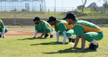 Tatbikat sırasında üç erkek beyzbol oyuncusu koni arkasında sahada çömelmeden bacak kaldırmaya doğru ilerliyorlardı. Sporcular, antrenman, dinamik, açık hava, fitness, takım çalışması, egzersiz