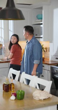 Dikey video: Asyalı çiftin mutfağı vazo için durulamasından sonra. Romantizm, uyum, yerli, yeşillik, dekor, yaşam tarzı, dikey video