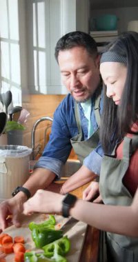 Dikey video: Asyalı çiftin biber dilimlemesi mutfak tezgahındaki çöp tenekelerine gübre atmaları. Yerli, aşçı, minimalist, çevre dostu, yaşam tarzı, yemek hazırlama, dikey video