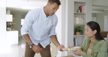 Orta yaşlı Afro-Amerikalı bir adam ve Asyalı bir kadın yemekten sonra yemek masasında tabak temizliyor. Ev işi, takım çalışması, yaşam tarzı, konforlu, çağdaş, uyum, gündelik