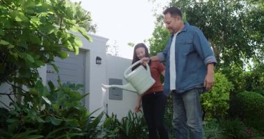 Çitleri budarken sulama tenekesi kullanarak dışarıda bahçeyle uğraşan olgun bir çift. Bahçıvanlık, çift, bahçıvanlık, doğa, açık hava, ekme, takım çalışması.