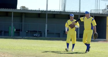 Gelen erkek oyuncular saha çimlerinde toplanıyor, eldivenle topu yakalıyorlar. Atletizm, takım çalışması, yoldaşlık, sportmenlik, açık hava, enerjik, rekabetçi