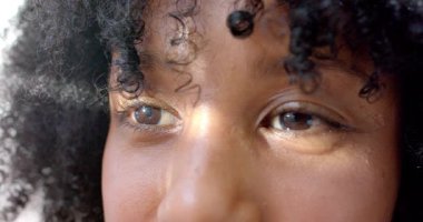 Aralıklı olarak göz kırpan yetişkin bir kadın. Güneş ışığı pencerenin yanındaki yüz boyunca sürükleniyor. Portre, doğal ışık, tefekkür, dinginlik, minimalist, iç gözlem, karamsar