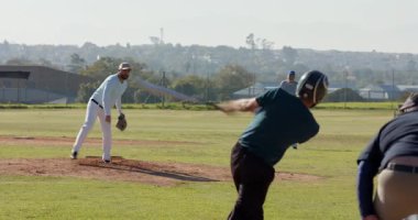 Beyzbol sahasında sahaya saha atışı yapan atıcı sahaya doğru yürüyor, kıdemli saha oyuncusu katılıyor. Spor, atletizm, yarışma, takım çalışması, açık hava, amatör, sıradan