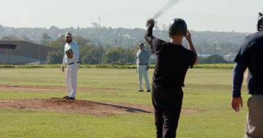 Atıcının ilk kaleciye bir bakışı tümsekte bitip beyzbolu dışarı fırlatıyor. Atletizm, sportmenlik, rekabet, takım çalışması, açık hava, aktivite, enerjik