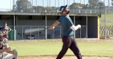 Top tutucu, vurucu erkek vurucunun vuruşunu işaret ediyor. Vuruş vuruşu için tekrar vurmaya çalışıyor. Atletik, takım çalışması, kararlılık, sportmenlik, açık hava, enerjik, rekabetçi