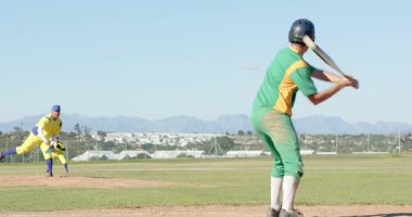 Atıştan sonra, beyaz vurucu ilk vuruşta koşuyor, atıcı ilk vuruşta topu atıyor. Atletizm, rekabet, aksiyon, canlı, açık hava, takım çalışması, odaklanma