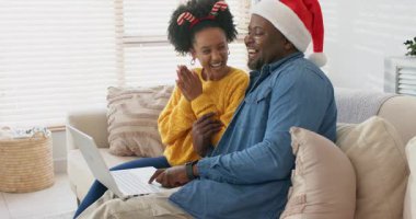 Çeşitli çiftler dizüstü bilgisayarlarında klavyelerini tıklatıyorlar tatil mesajlarını gösteriyorlar, evdeki kanepede gülüyorlar. Samimiyet, samimiyet, kutlama, şenlik, bağlantı, rahatlama, iç mekan