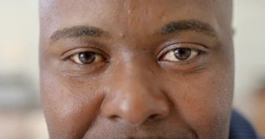 Kırpıyor ve gözlerini dikiyor, orta yaşlı Afro-Amerikan bir adam yumuşak iç mekanda nazik bir gülümseme oluşturuyor. Portre, iç gözlem, dinginlik, bağlantı, farkındalık, rahatlama, çağdaş