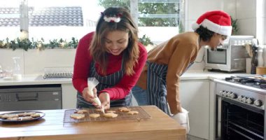 Kurabiyelerin üzerine çeşitli çiftler soğutma boruları serinletiyor sonra da sıcak tepsileri çekerek mutfakta ikramlar hazırlıyorlar. Şenlik, tatil, pişirme, kutlama, aşçılık, konfor, ev