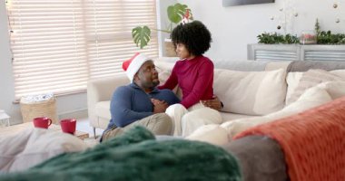 Kanepeye yaklaşan kadın, evde partnerinin omuzlarına dokunarak hassas bir an yaşıyor. Şefkat, samimiyet, konfor, şenlik, sıcaklık, arkadaşlık, rahatlama.