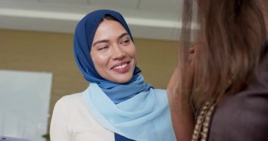 Tablet kullanan Hintli kadın iş arkadaşına gülümseyip işaret ediyor sonra da düşünceli bir şekilde ofisine bakıyor. İşbirliği, takım çalışması, profesyonel, iş, modern, iletişim, çeşitlilik