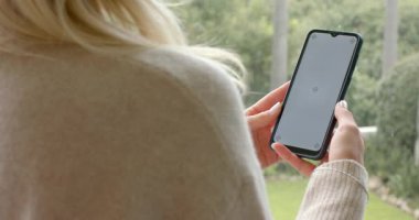 Boş ekrandan sonra, kadın akıllı telefonu döndürüyor ve bahçe balkonunda görüş açısını değiştiriyor. Doğa, rahatlama, açık hava, her zaman yeşil, huzur, yaşam tarzı, modern.